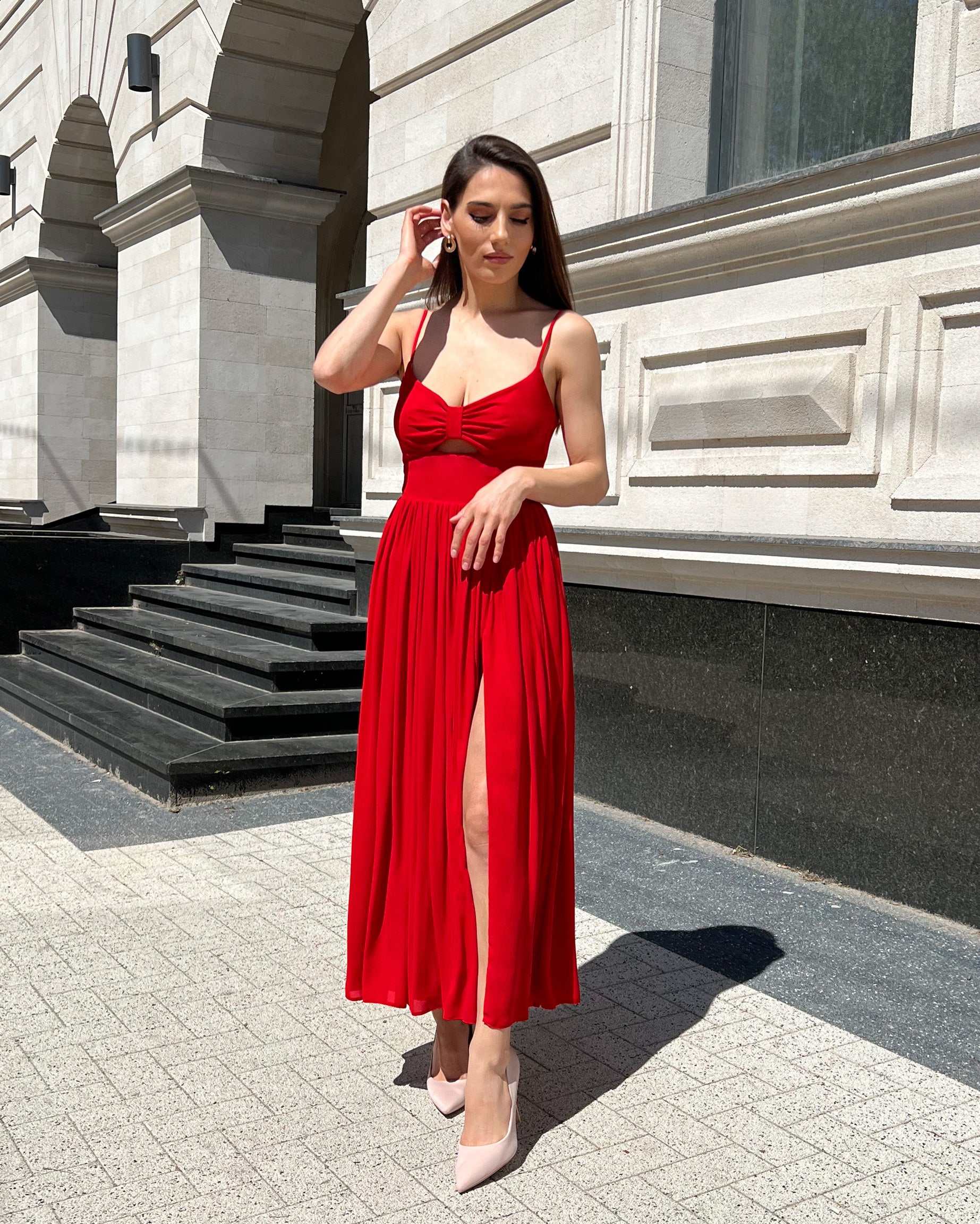 Rochie rosie midi elegantă cu bretele subțiri și decupaj frontal.