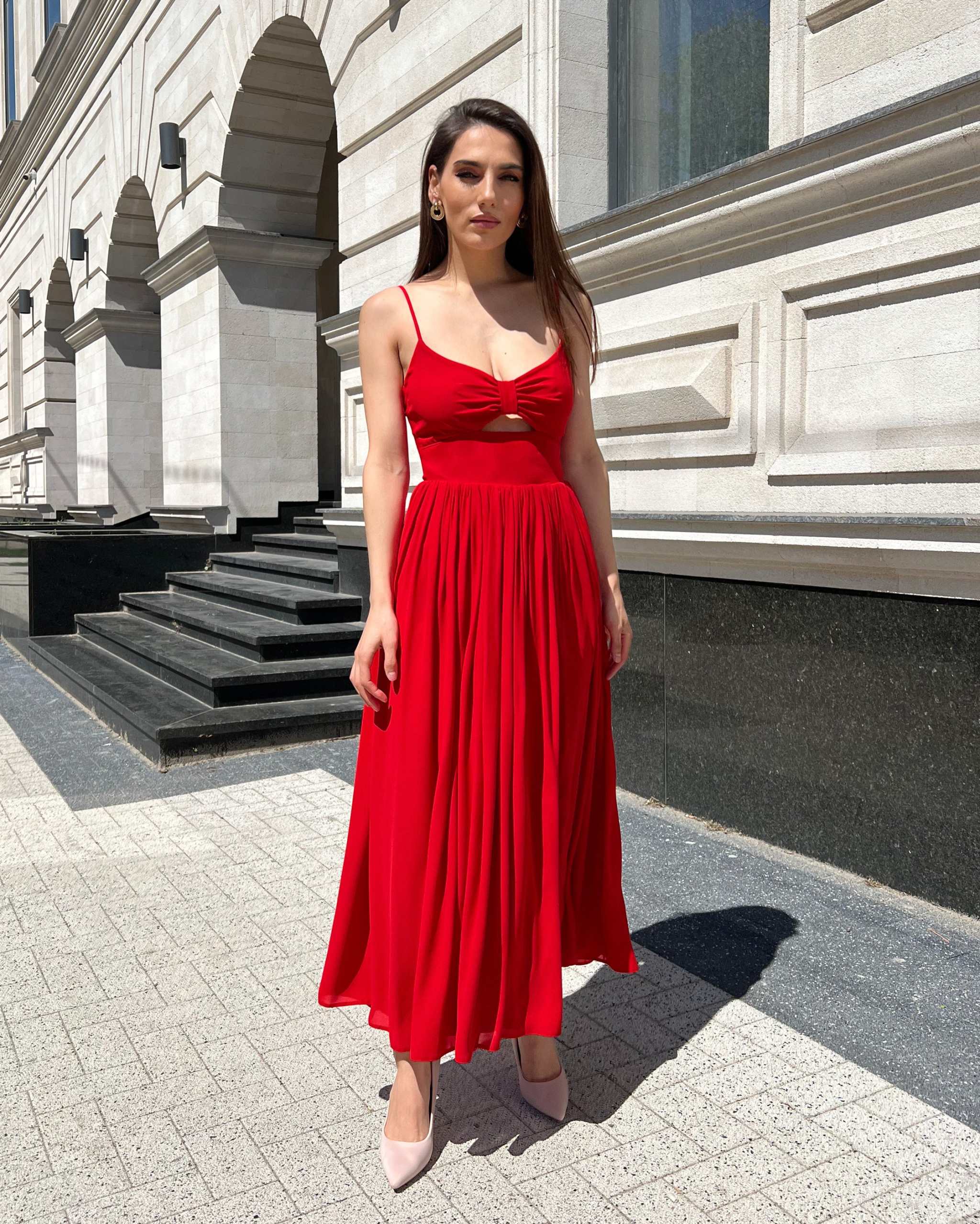 Rochie rosie midi elegantă cu bretele subțiri și decupaj frontal, potrivită pentru evenimente speciale.