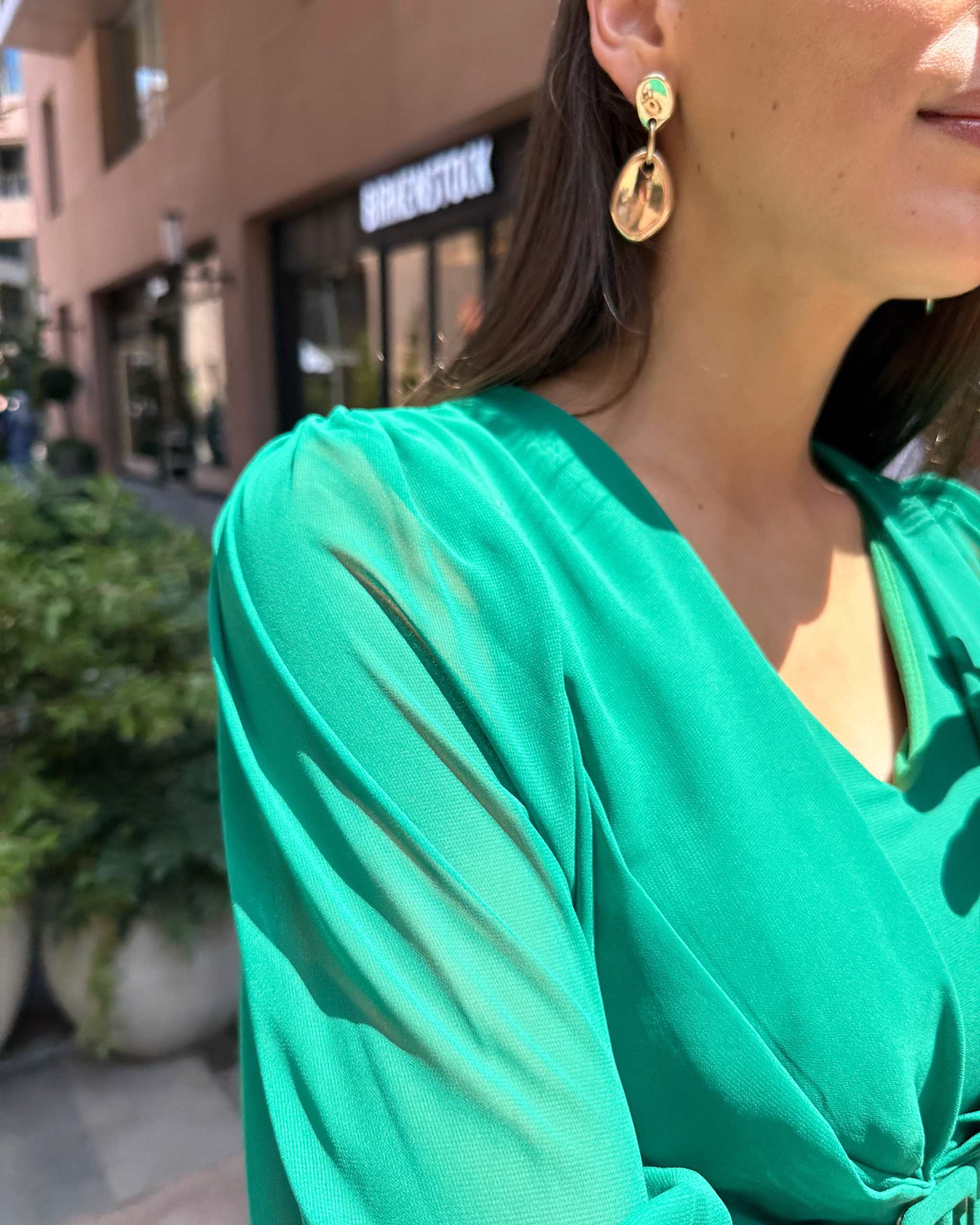 Rochie verde elegantă cu mâneci, drapaj și fermoar la spate.