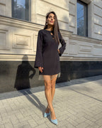 Rochie neagra scurtă cu franjuri din cristale și mâneci lungi, detaliu decorativ pe partea superioară.