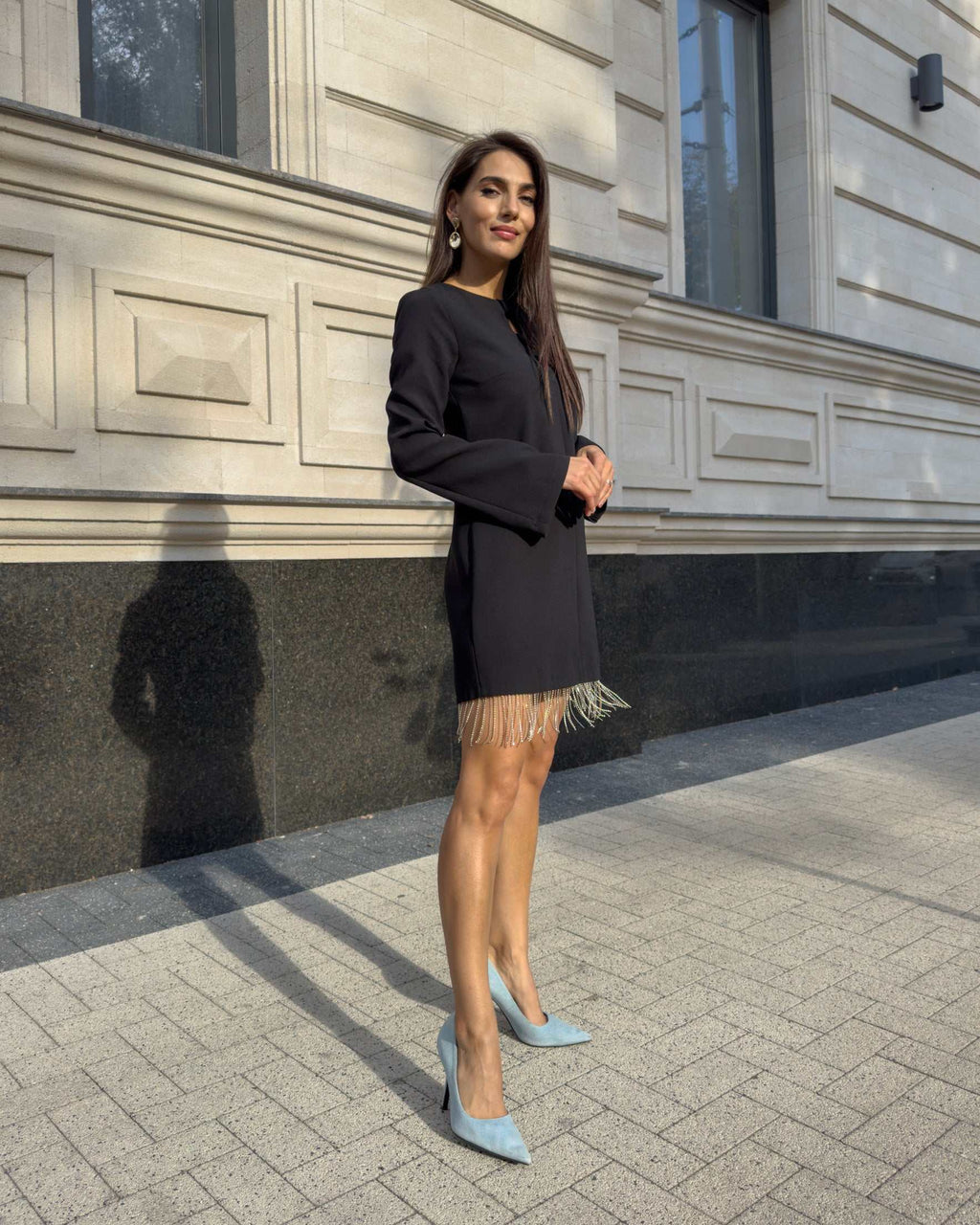 Rochie neagra scurtă cu franjuri din cristale și mâneci lungi, detalii decorative, purtată afară.