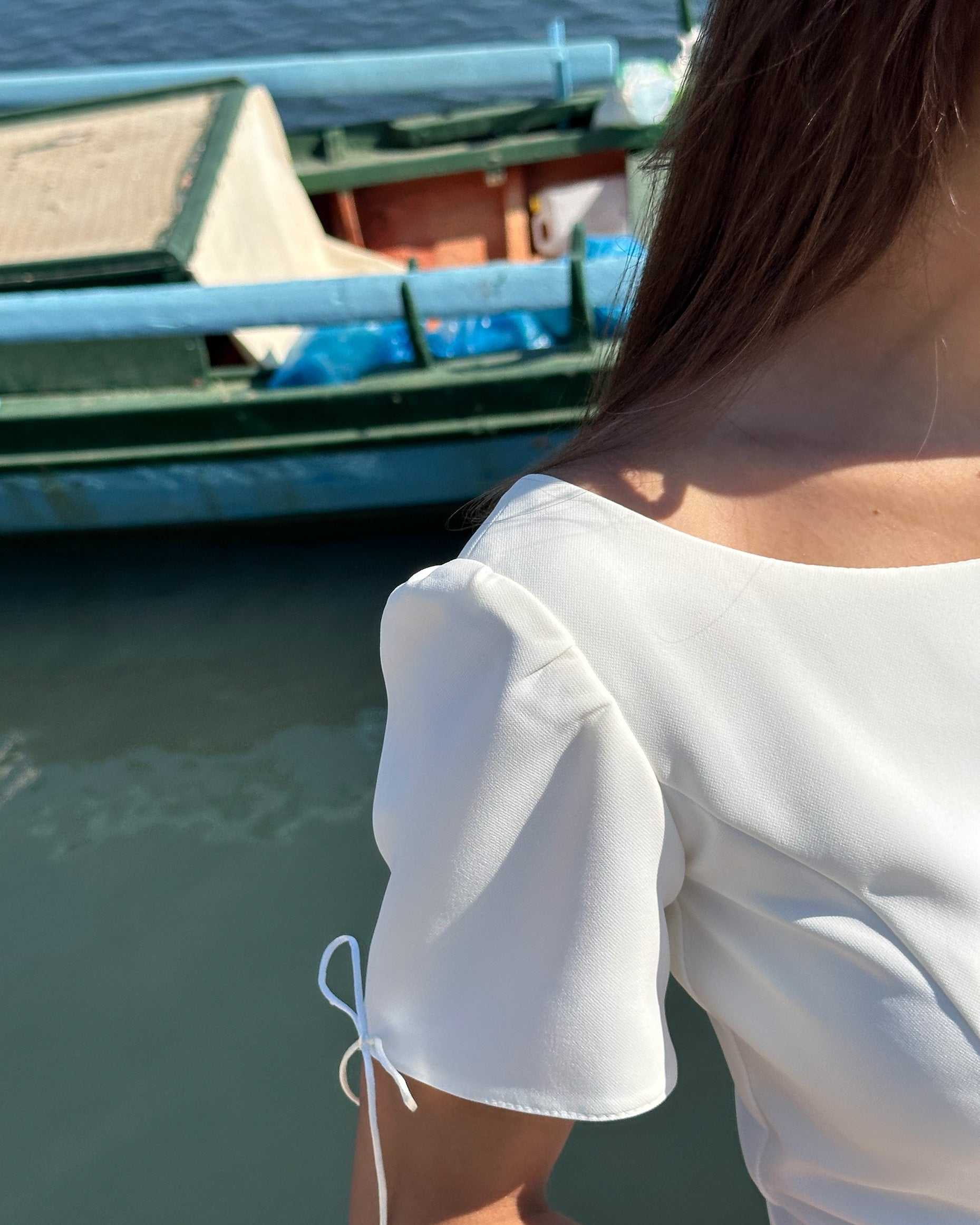 Rochie albă scurtă cloș cu mâneci semielastice, detalii feminine și elegante.