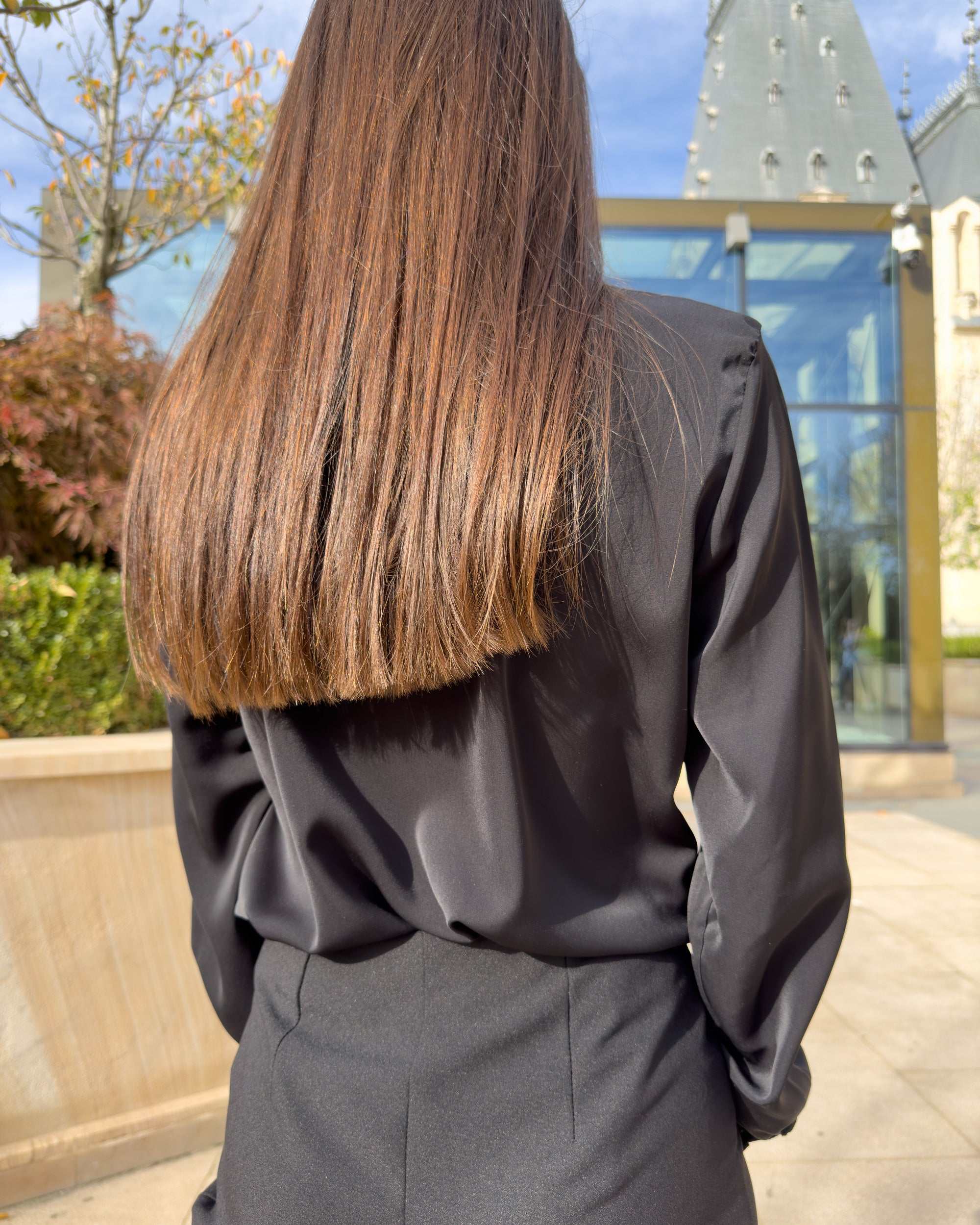 Bluza dama neagra cu guler din satin, detaliu decorativ la bust și mâneci lungi.