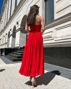 Rochie rosie midi cu bretele subțiri, design elegant și decupaj frontal.