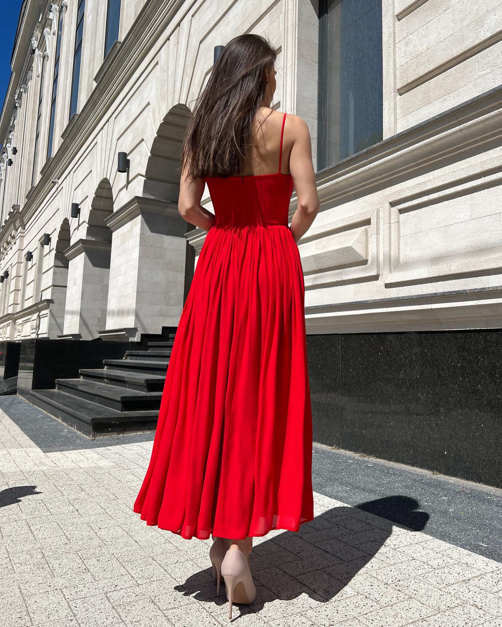 Rochie rosie midi cu bretele subțiri, design elegant și decupaj frontal.