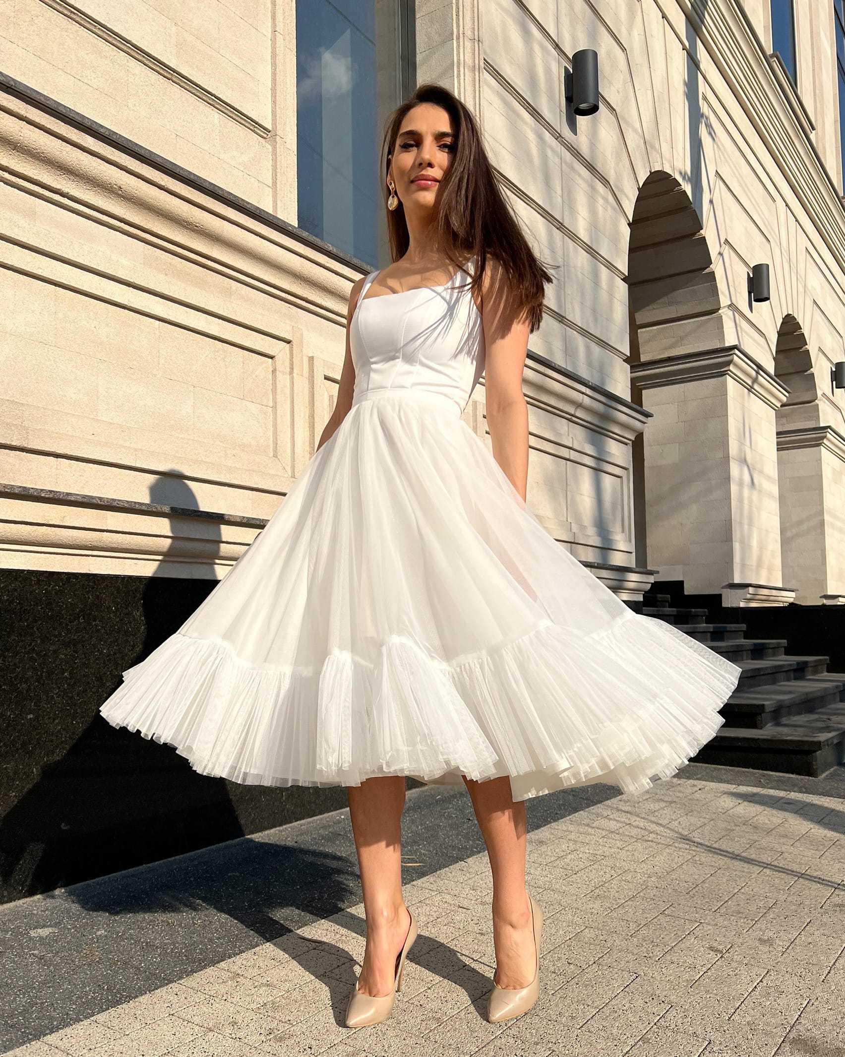 Rochie cununie civila albă elegantă midi cu decolteu în fața unei clădiri.