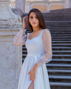 Rochie de mireasa albă lungă din satin cu șliț, mâneci transparente, elegantă.